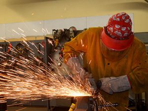 Sparks fly as student welds in a metal shop.