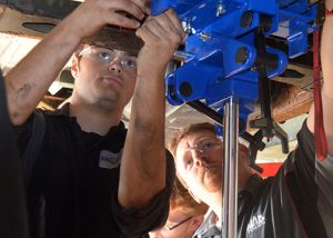 A student and teacher work on a car.