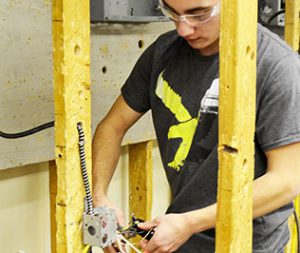 Student holding pliers working with wiring.