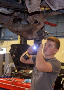 Automotive Tech Graduate Chris Goodrich works on the underside of a vehicle.