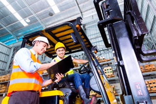 A fork lift driver and job foreman in a warehouse review a checklist.