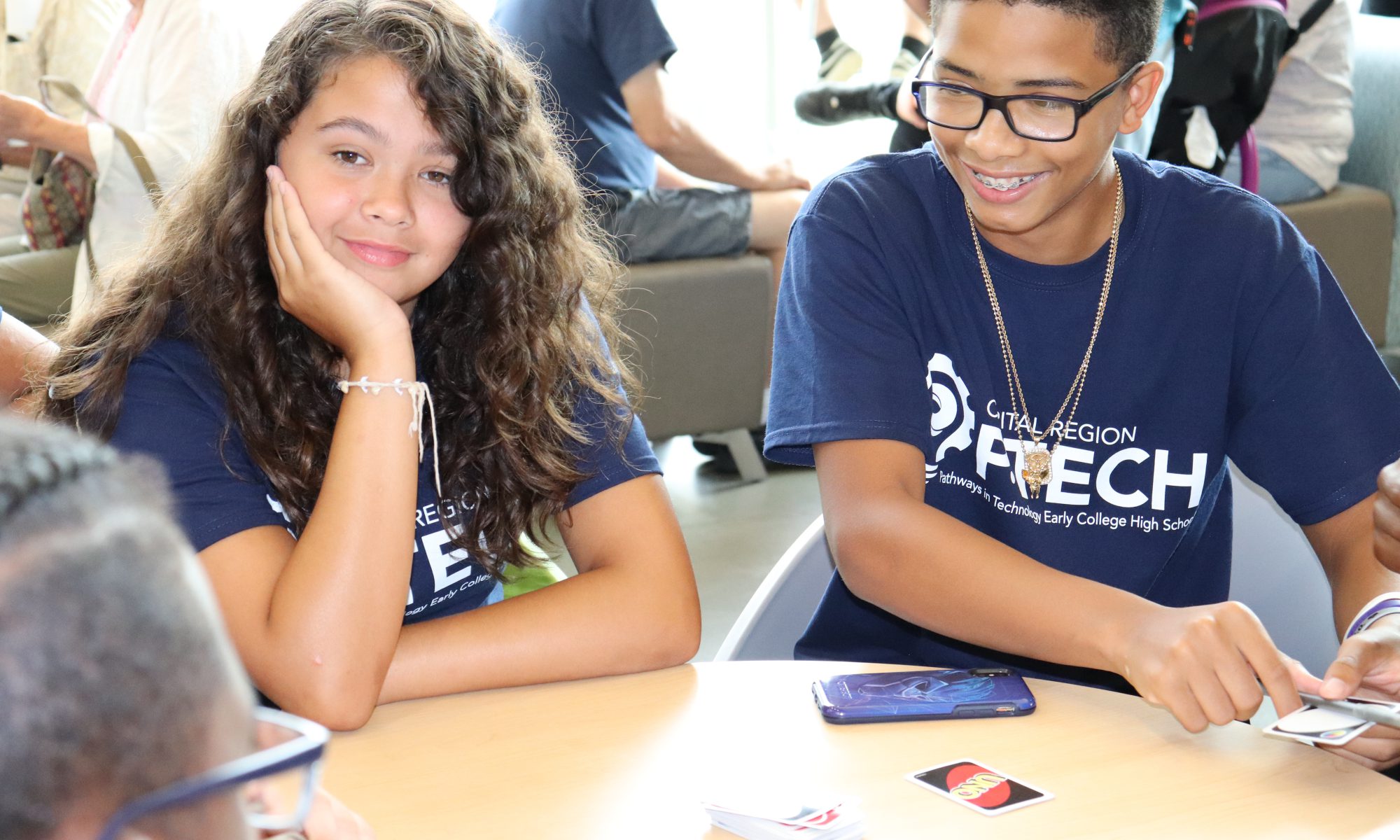 Watervliet Freshman Melissa Mayo and male P-TECH student smile as they play a card game with a classmate.