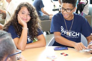 Watervliet Freshman Melissa Mayo and male P-TECH student smile as they play a card game with a classmate.