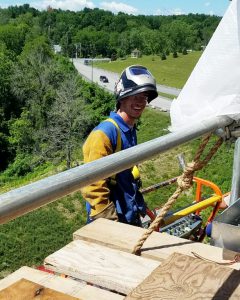 Career and Technical School graduate Ian Mayo poses on a scaffold high above the ground. 