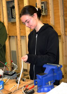 Career and Technical School student Sydney Rickard holds wires in her hand.