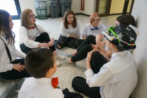 Middle school students sit in a circle and talk together before their Odyssey of the Mind presentation.