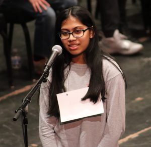 A middle school girl spells a word into a microphone during the Regional Spelling Bee at Proctors Theatre.
