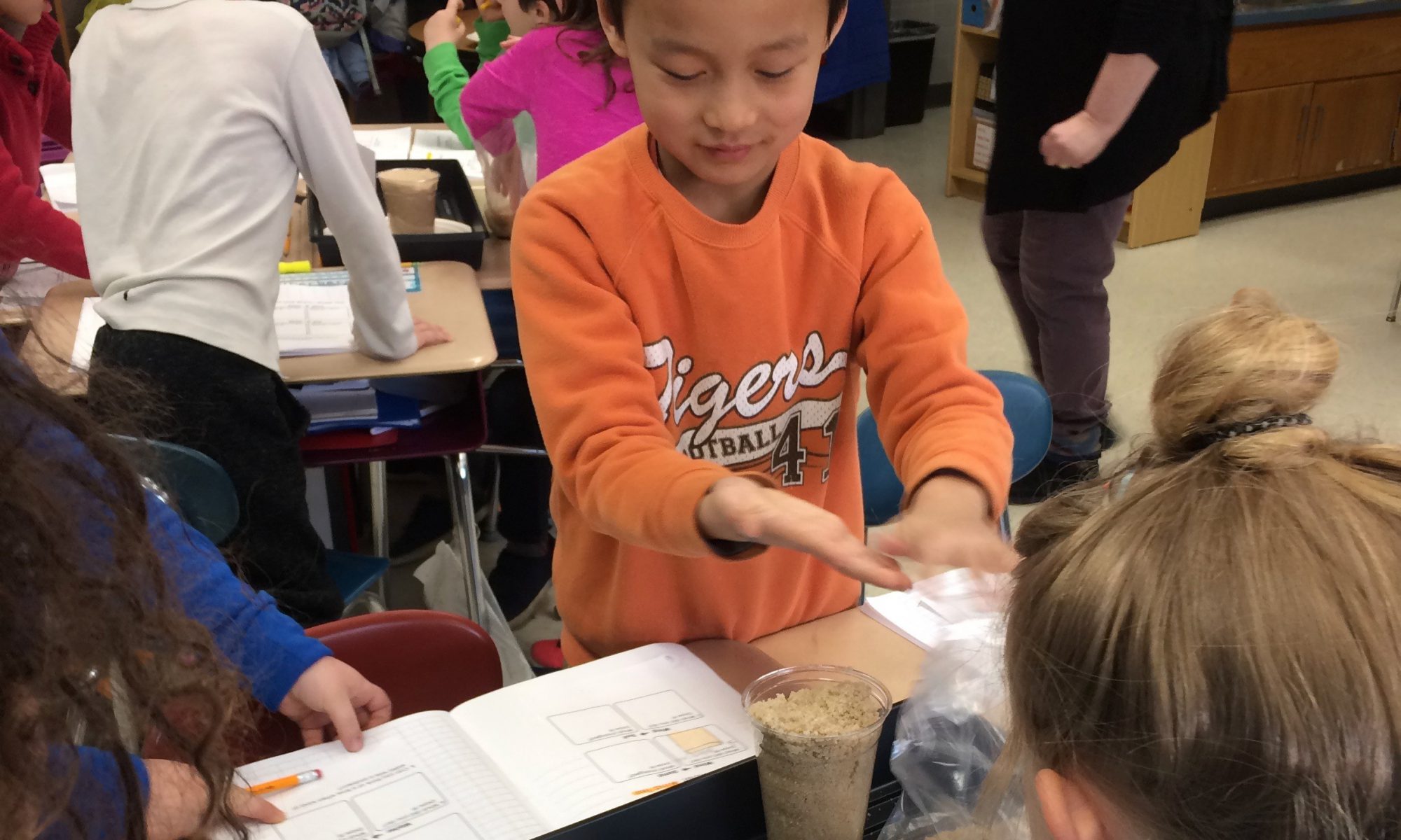 A group of second grade students test their engineering designs to protect a sand castle from flooding.