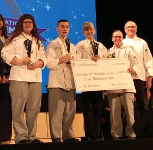 Career and Technical School Culinary students and their teachers pose with a large scholarship check.