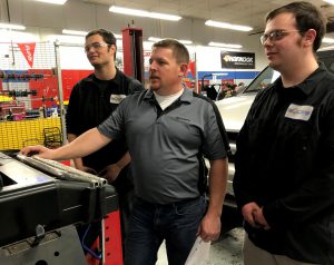 Teacher Brian LaCroix works with two students in his BOCES automotive classroom.