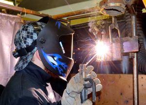 Capital Region BOCES Adult Welding and Metal Fabrication student Tom Resso wears a welding helmit as he works with a mig gun.
