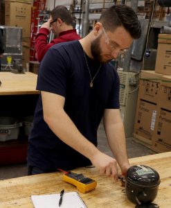 Senior Mark Molesky works with a machine at a table in a Heating, Ventilation, Air Conditioning and Refrigeration classroom.