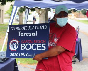 grad holds congratulatory sign for camera