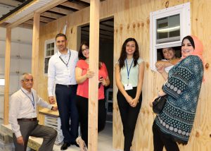 Educators from Palestine and Capital Region BOCES pose for a photos in front of an unfinished wooden shed built by students.