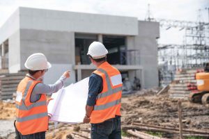 Two construction workers look on to project in progress. 