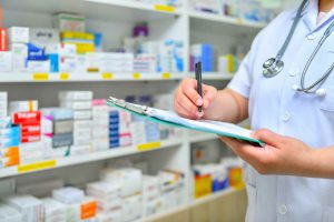 Pharmacist writes on a clipboard.