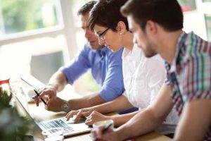 Three people work at a computer together