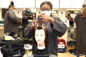 A student in the Capital Region BOCES cosmetology program works on the hair of a mannequin.