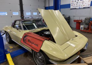 A yellow 1967 Corvette with its hood raised is parked in a bay of a garage at the Capital Region BOCES Career & Technical School.