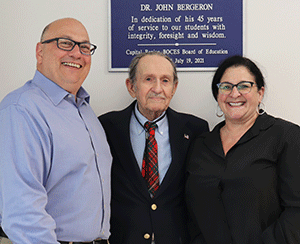 Capital Region BOCES' Senior Executive Officer Joseph P. Dragone, Longtime Board Member Dr. John Bergeron, and District Superintendent Anita Murphy look at and smile for the camera during a dedication of Airline Drive Academy in Bergeron's honor.