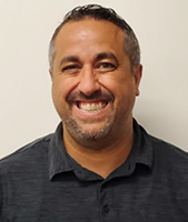 Gabriele Barbato, who has short brown hair and a closely trimmed beard and mustache, looks at and smiles for the camera.