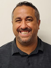 Gabriele Barbato, who has short brown hair and a closely trimmed beard and mustache, looks at and smiles for the camera.
