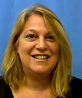 Health Careers & Services Principal Paula Negri, who has shoulder length blond hair and is wearing a dark blue blouse, looks at and smiles for the camera.