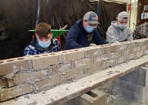 three Construction/Heavy Equipment students learning masonry