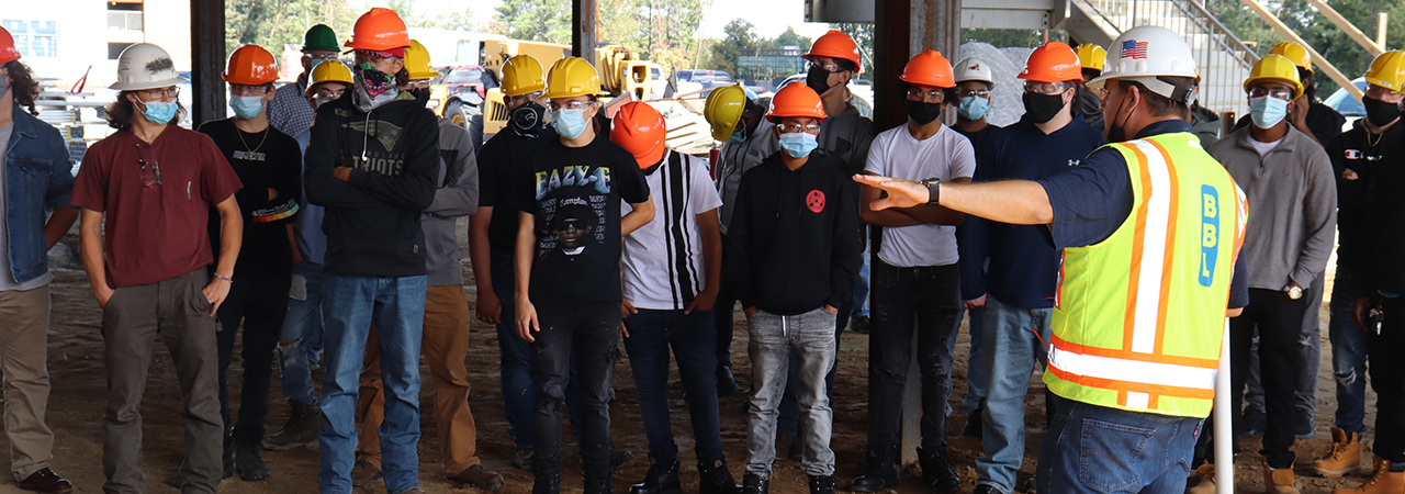 Group of student with instructors near construction equipment