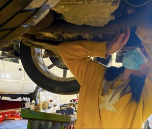 Kiersten Acer, automotive engine repair student, working on a car that's on a lift