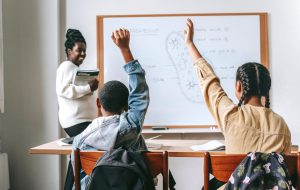 Students raising their hands in class.