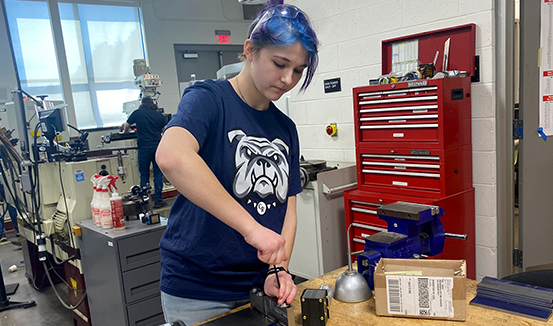 A CTE student wearing protective eyewear works on a metal project.