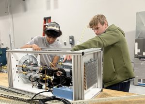 Two students, Vincent and Matt, working on a piece of HVAC/R equipment.