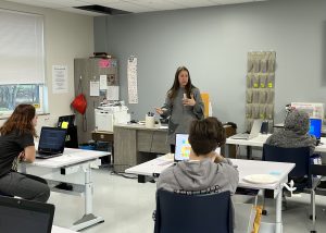 Annmarie Lanesey from CanCode Communities speaks to students at the front of a classroom.