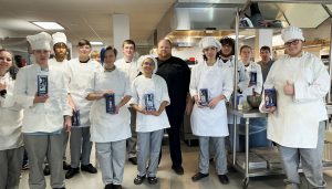 Jason Eksterowicz poses with Culinary Arts students. The students are holding New York Mets bobble head figures.