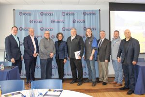 A photo of nine individuals smiling and standing next to one another, in front of a blue backdrop that has the Capital Region BOCES logo.