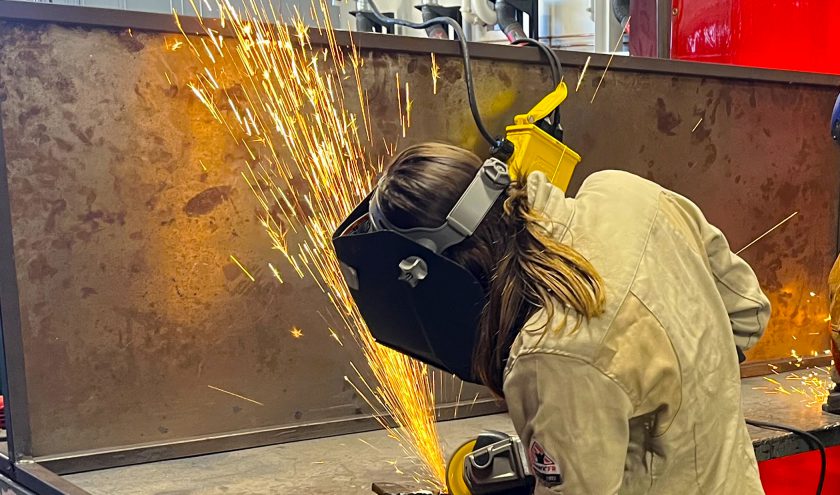 A CTE student wearing protective eyewear works on a metal project.