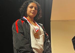 Angelina Depina Desorbo wearing a black and red SkillsUSA jacket wears a medal