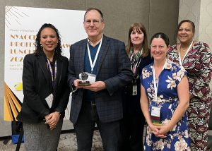 Frank Finch stands with four members of NYACCE as he holds an award.