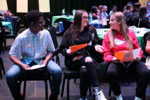 Three students sitting next to each other, in conversation.