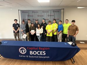 A group photo of 12 students in front of a backdrop with the Capital Region BOCES logo. 