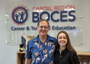 Frank Finch (left) and Tetiana Prokopenko (right) smile in front of a sign that says Capital Region BOCES Career & Technical Education.