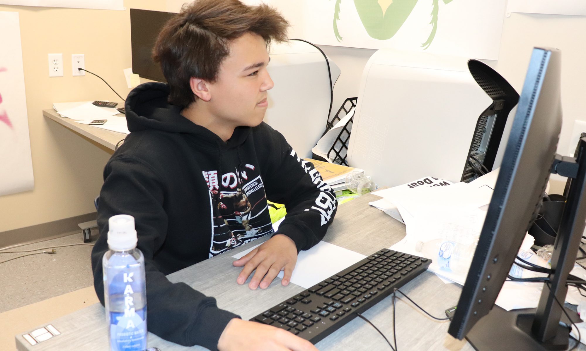 RCS High School student Evan Agan works in front of a computer with a mouse in his hand.