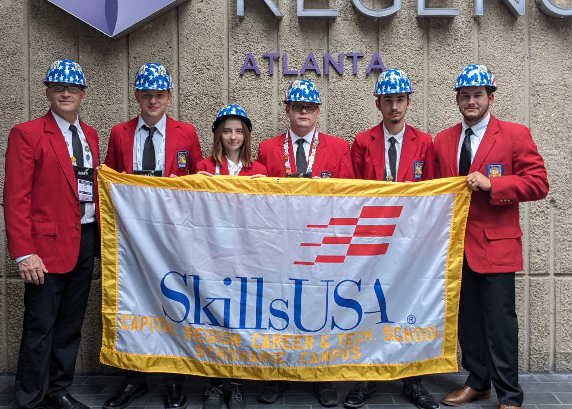 Six students in hard hats hold a banner that reads SkillsUSA.
