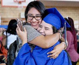 A graduate hugs a friend or family member following graduation ceremonies.