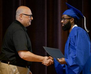 A graduate shakes hands with Capital Region BOCES' Senior Executive Officer Joseph P. Dragone after receiving his diploma.