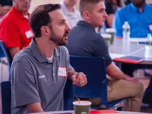 A bearded man in a grey polo speaks during a roundtable discussion hosted by Capital Region BOCES