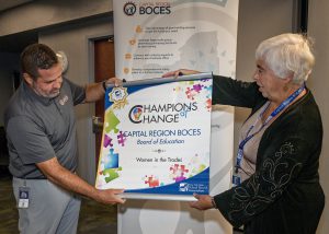 A group of BOCES employees line up holding a banner that reads "Champions of Change."