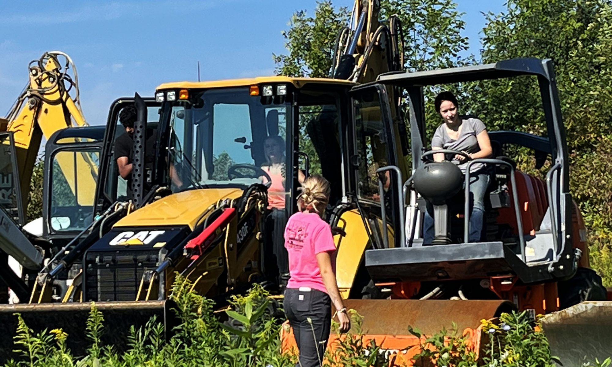 Two students are each pictured behind the wheel of their respective earth-moving machine.