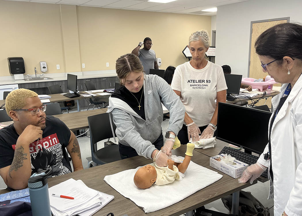 Chris James, of Albany, Trinity Santoro, of Schoharie, and Beth Longale, of Colonie, look over a young patient during Linda Keifer's class.